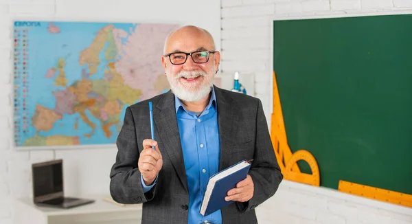 Passar o tempo tentando. sala de aula com mapa e quadro negro. de volta à escola. educação na escola retro. O homem barbudo dá marcas no diário. escrever notas no livro. Professora sénior faz anotações. professor de geografia — Fotografia de Stock