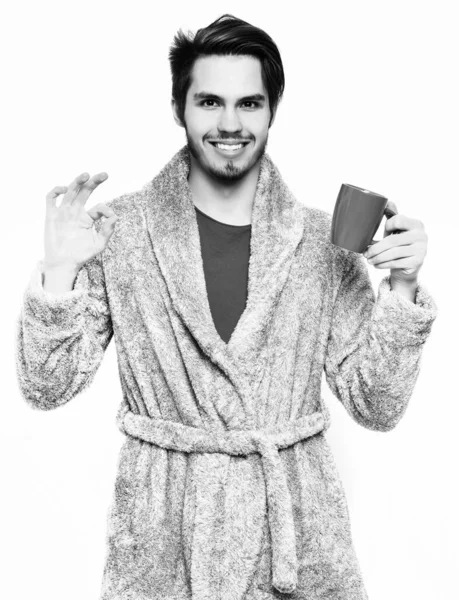 Красивий бородатий усміхнений чоловік з чашкою в махровому халаті — стокове фото