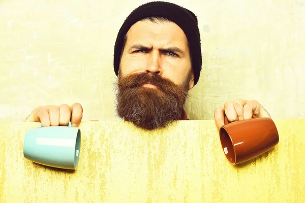 Barbudo brutal hipster caucásico con hoja de papel y tazas —  Fotos de Stock