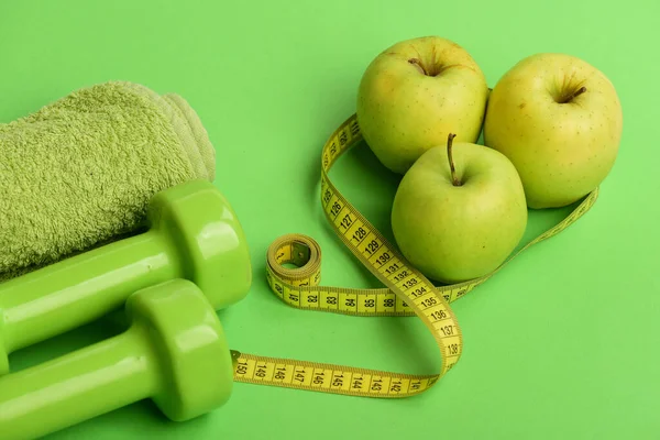 Hantlar i klargrön färg, måttband, handduk och frukt — Stockfoto