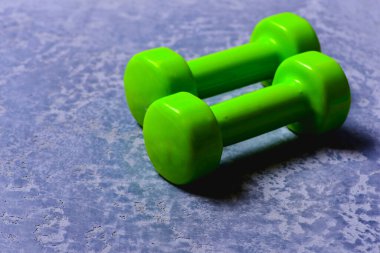 Spor ve sağlıklı yaşam tarzı kavramı. Yeşil plastikten yapılmış dambıllar