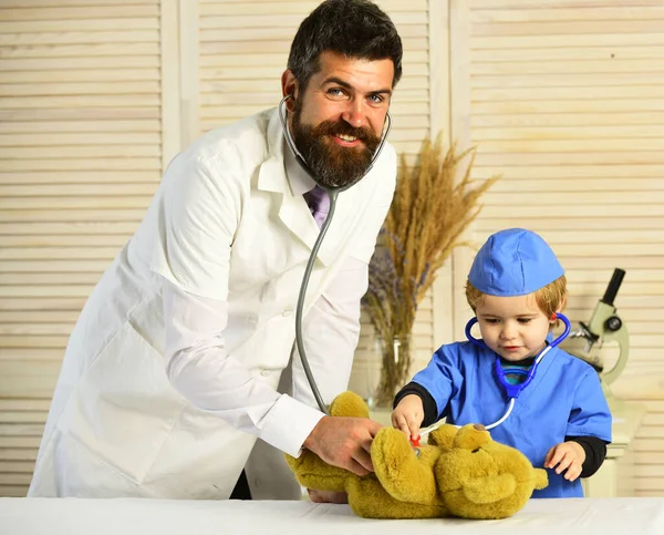 Pediatra y asistente examinan osito de peluche. Padre e hijo — Foto de Stock