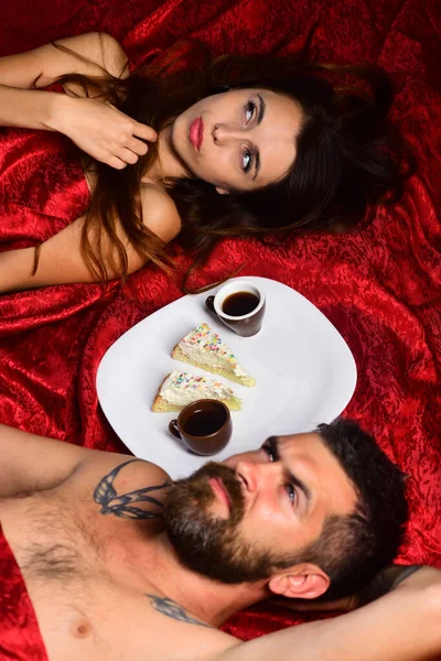 Couple amoureux sur des draps rouges. Homme barbu — Photo