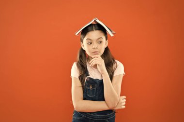 Ev ödevi konsepti. Evde eğitim ve özel ders. Kafasına kitap. Küçük kız kitap çatı başkanı. Küçük kız kitap turuncu arka plan. Çocuk için ilginç bir hikaye. Çalışmak ve dinlenmek. Evde eğitim