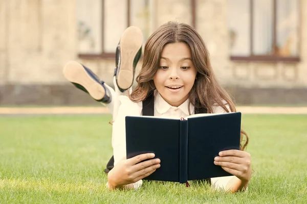 Il ne pourrait y avoir de vérité sans information. Small child get information from library book. Jolie petite fille lue sur l'herbe verte. Informations scolaires. Éducation et information — Photo