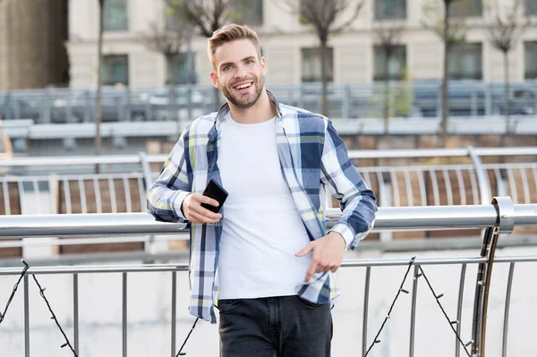 Muž v kostkované košili. student používající moderní smartphone v blízkosti kanceláře na ulici. portrét mladého podnikatele držícího mobil. Mladý městský profesionál používající chytrý telefon. přenosná kancelář — Stock fotografie