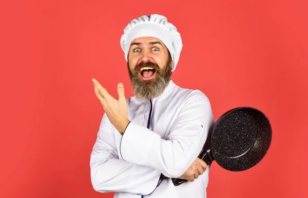 Бородатая форма повара Мужчина держит сковороду. Готовишь как профессионал. Легкие дешевые вкусные блюда, приготовленные в домашних условиях. Будьте очень осторожны. Готовлю еду на кухне. Концепция приготовления пищи. Высокое качество сковороды — стоковое фото