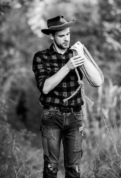 Dono do rancho. Ferramenta de laço. Cowboy americano. Laço amarrado embrulhado. A vida ocidental. Conceito de criação de Seattle. Cowboy no campo. Ocupações no rancho. Homem cowboy natureza fundo. Homem usando chapéu segurar corda — Fotografia de Stock