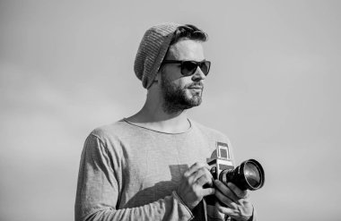 Hipster muhabir fotoğraf çekiyor. Dışarıdaki fotoğrafçı arka planda. Fotomuhabir konsepti. Gezgin blogcu. Profesyonel fotoğrafçı. Yakışıklı fotoğrafçı retro kamera. Elle ayarlar