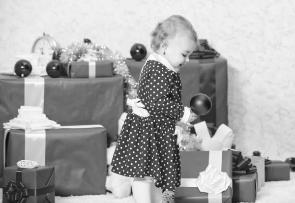 Вещи, связанные с малышами на Рождество. Рождественские подарки для малыша. Подарки для первого ребенка. Маленькая девочка играет рядом с кучей подарочных коробок. Семейный праздник. Празднование первого Рождества — стоковое фото