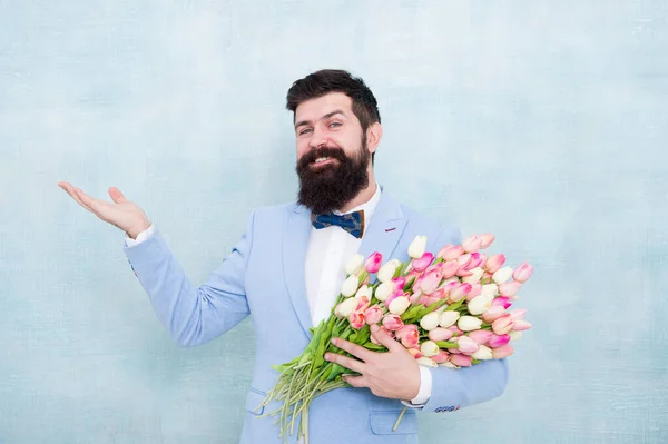 Choose and order gift. Bearded man with fresh flowering gift. Happy hipster with tulip bunch. Floral gift for Valentines day. Valentines gift for women. Valentine man hold empty hand for copy space