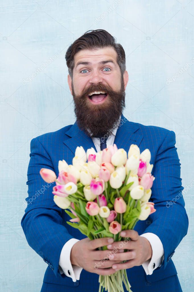 Spring holidays. prepare for mothers day holiday. flower surprise for her. bearded man in formal suit greeting. happy valentines day. womens day gift tulips. spring flowers. Man with bouquet tulips