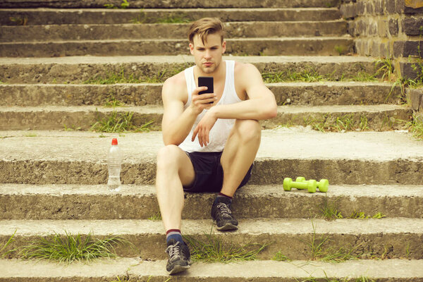 Man with concentrated face expression sitting on stairs with phone