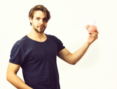 Beyaz seksi genç maço elinde pembe domuz kumbarası tutuyor.