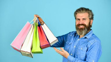 İnternetten alışveriş yapmak büyük zevk. Elektronik mağazasından alışveriş yapan son derece mutlu bir hippi. Alışverişten hoşlanan olumlu bir adam. Kendi işim var. Sakallı adam kese kağıdı tutuyor. sunar