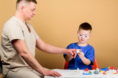 İlk yardım. Tıbbi yardım. Travma ve yaralanma. Tıp konsepti. Küçük doktor, masada tıbbi aletlerle oturuyor. Sağlık hizmetleri. Tıbbi muayene. Tatlı çocuk ve babası doktor. Hastane çalışanı