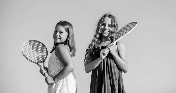 Nunca pares. actividad deportiva de verano. niños enérgicos. feliz y alegre. juego deportivo. juegos al aire libre de verano. jugar al tenis. felicidad infantil y hermandad. niñas pequeñas con raqueta de tenis — Foto de Stock