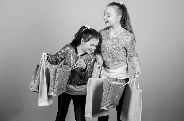 Zwarte vrijdag. Verkoop en korting. Winkeldag. Kinderen hebben pakketjes. Kindermode. Verwacht meer. Betaal minder. Meisjes zussen vrienden met boodschappentassen beige achtergrond. Winkelen en kopen — Stockfoto