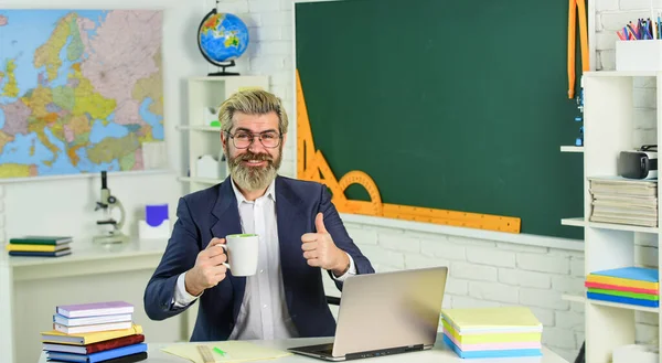 Good drink for good work. Bearded man with cup give thumb up. Senior teacher drink coffee in class. Hot caffeine drink. Tasty drink recipe. School break. Breaktime. Learning and teaching