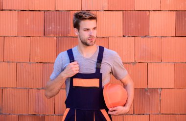 Foreman plan yapıyor. Adam ev inşa ediyor. Becerikli mimar tamir ve onarım. Bina ve inşaat. İşçi tuğlası arka plan. İş kıyafetleri içinde bir erkek müteahhit. Profesyonel tamirci şapkası.