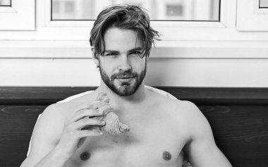 Yatak odasında cep telefonuyla uyandırılan uyuyan adam. Büyük çıplak kaslı adam yatak odasında eğleniyor. Sakallı yakışıklı adam yatakta kahvaltı yapıyor. Kahve içen seksi adam..