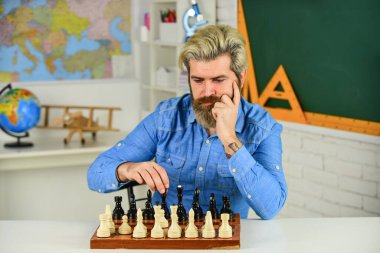 Masa Oyunları Kralı. Rakip satranç taşlarına saldırmayı düşünüyorum. Bir sonraki hamleyi düşünüyorum. Satranç yarışması için sakallı adam eğitimi. Tahta üzerinde satranç figürleri. Odaklanmış okul öğretmeni