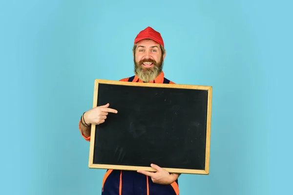 Een reparateur. Bouwvakker. Reparatietechniek. Huishoudbedrijf. Diensten die wij aanbieden. De monteur verricht technisch werk. Man werknemer houden schoolbord kopieerruimte. Elektricien loodgieter klusser — Stockfoto