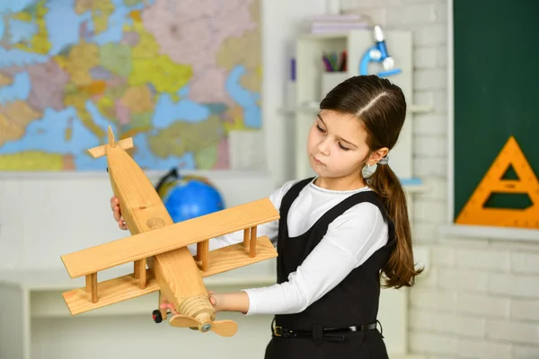 Klein meisje spelen met speelgoed vliegtuig. Vlieger met vliegtuigdromen. retro houten speelgoed in modern onderwijs. Vlieg op het vliegtuig. Concept van dromen en reizen. terug naar school. stam. willen reizen — Stockfoto