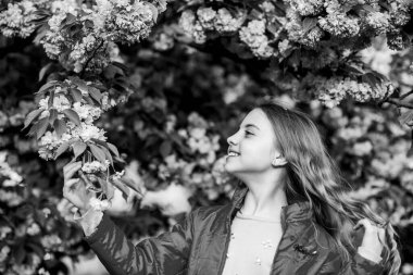 Bahar zamanı cilt için doğal kozmetik ürünleri. Bahar çiçeğindeki küçük kız çocuğu çiçek açar. Kiraz çiçekli mutlu kız. Sakura ağacı çiçek açıyor. Çiçek kokusu, alerji. Yaz. Çocukluk güzelliği