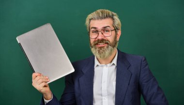 Sakallı adam, modern dizüstü bilgisayar internette sörf yapıyor. İlginç bir bilgi. Geçerli doğru bilgileri sağlayın. Okulun cankurtaranı. Öğretmen gözlük takıyor dizüstü bilgisayarı tutuyor internette sörf yapıyor. Çok fazla bilgi