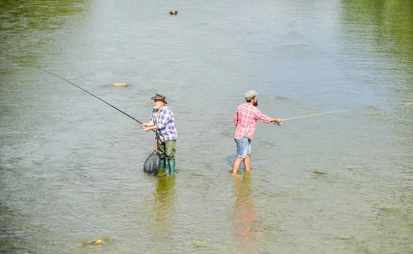 Tief im Wasser. Hobby und sportliche Betätigung. Forellenköder. zwei glückliche Fischer mit Angelrute. Großwildfischen. Männerfreundschaft. Vater und Sohn angeln. Abenteuer. Erholung und Freizeit im Freien — Stockfoto