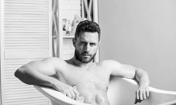 Macho naked in bathtub. Wash off foam with water carefully. Sex and relaxation concept. Macho attractive nude guy. Sexy man in bathroom. man wash muscular body with foam sponge. massage relaxation — Stock Photo, Image