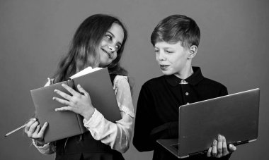 Ders zamanı. Küçük çocuklar bilgi dersi alır. Küçük kız ve oğlan ders kitabı ve dizüstü bilgisayar kullanıyor. Okul konusu mu, ders mi? Bilgi ve iletişim teknolojisi eğitimi. Çevrimiçi eğitim