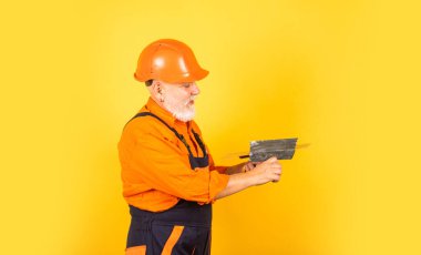 Biraz molaya ihtiyacı var. Üniformalı sıvacı. Spatulalı adam. Macun katmanının uygulanması işlemi. Sıva için alçı aletleri. alçıpan alçıpanında alçıpan spatulası