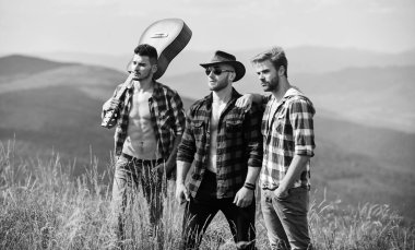 Macera Takımı. Uzun yol. Turistler yürüyüş konsepti. Arkadaşlarla yürüyüş. Güneşli bir günde gitar çalan adamlar. Kareli gömlekli bir grup genç dağın tepesinde birlikte yürüyorlar.