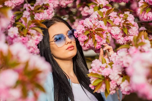 Aksesuar dükkanı. Sakura ona yakışıyor. Muhteşem çiçek ve dişi güzellik. Bahar çiçeğinin açtığı süslü güneş gözlüklü kadın. Kiraz çiçekli kız. Bahar moda koleksiyonu. Sakura ağacı çiçek açıyor. — Stok fotoğraf