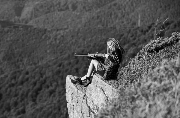 Hunter berg landskap bakgrund. Sexig krigare. Kvinna attraktiv långt hår vackra ansikte hålla gevär för jakt. Amazon flicka sitta på klippan förbereda pistol för jakt. Syftar till koncept. Jaktsäsong — Stockfoto