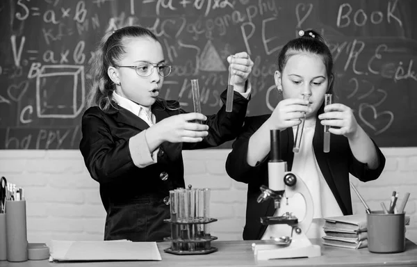 Microscope and test tubes on table. Perform chemical reactions. Basic knowledge of chemistry. Girls classmates study chemistry. Make studying chemistry interesting. Educational experiment concept