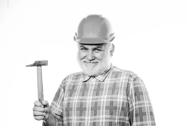 经验丰富的工程师修理或翻新。住房改善维修。留胡子的工人戴着头盔拿着锤子.修理车间。修理的概念。高级工头。勤杂工修理房屋 — 图库照片