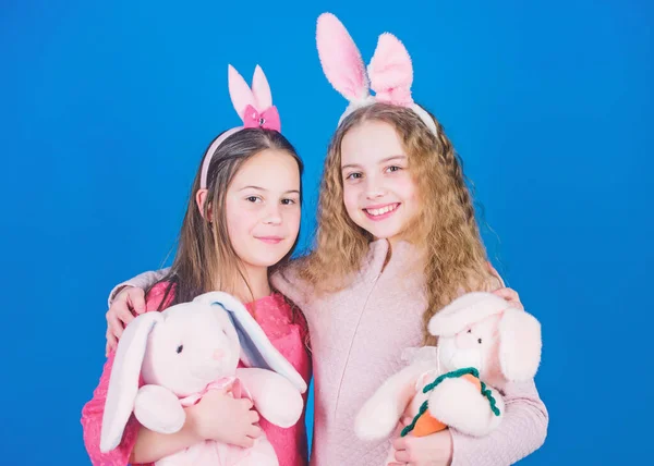 Sisters smiling cute bunny costumes. Spread joy and happiness around. Hope love and joyful living. Friends little girls with bunny ears celebrate Easter. Children with bunny toys on blue background — Stock Photo, Image