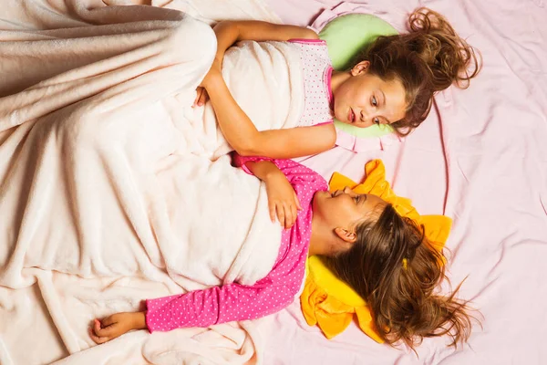 Schoolgirls have rest in bed looking at each other. — Stock Photo, Image