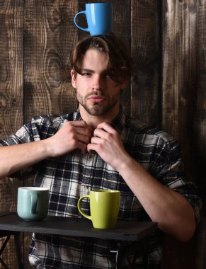 Ahşap arka planda bardakları tutan yakışıklı adam.