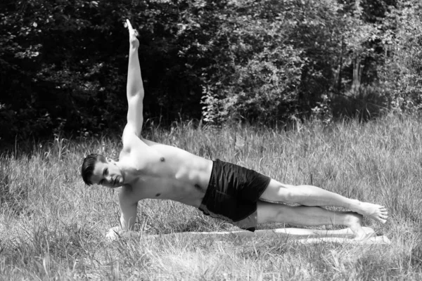 Homem esportivo com seis pacotes faz exercícios no tapete de ioga — Fotografia de Stock