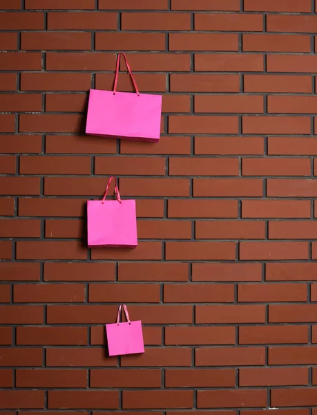 Sacos de compras rosa no fundo da parede de tijolo — Fotografia de Stock