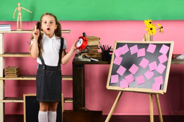 Sürpriz yüz fikir sahip olmak ile kız öğrenci kırmızı saat tutar