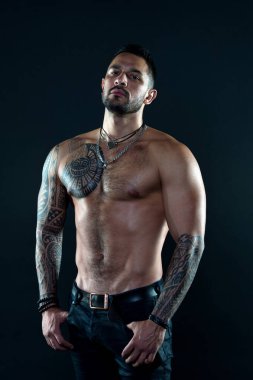 Spor ve spor. Erkeklik. Kaslı gövde. Baştan çıkarıcı bir bakış. Dövmeli sakallı bir adam. Maço seksi çıplak gövde. Cildinde dövme resmi olan uygun bir model. Sakallı ve saçlı sporcu ya da sporcu