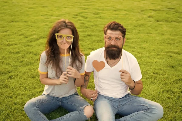 Casal no amor adereços de cabine de jovens alegres. Pessoas emotivas. Homem barbudo hipster e bonita mulher rostos alegres. Jornada da juventude. Entretenimento de verão. Casal namoro. Casal despreocupado se divertindo gramado verde — Fotografia de Stock