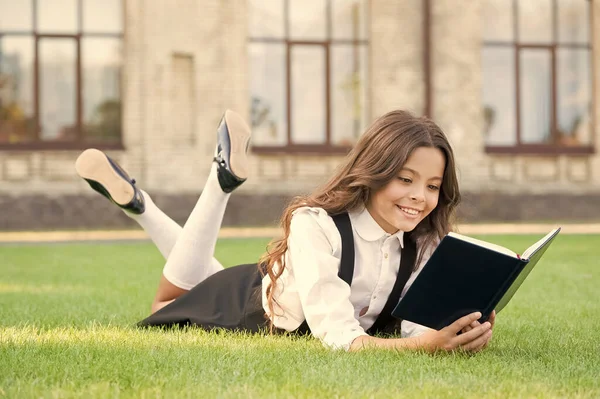 Jeden Tag lesen. Nettes kleines Kind liest Bibliotheksbuch auf grünem Gras. entzückendes kleines Mädchen, das in der Freizeit lesen lernt. Lesen als Hobby. ich lese überall — Stockfoto