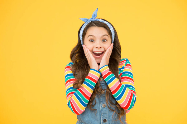 детское счастье. У ребенка длинные вьющиеся волосы. удивлённая маленькая девочка носит ретро-платок. Детская мода. быть позитивным и стильным этой весной. женский аксессуар для модного вида. копировальное пространство