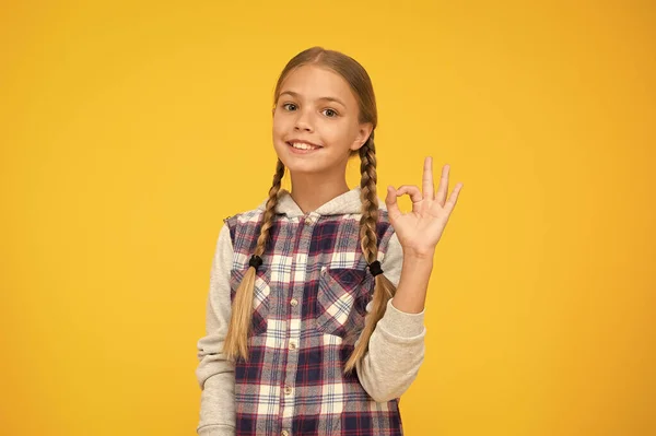 Po prostu świetnie. Szczęśliwego międzynarodowego dnia dla dzieci. Żółte tło małej dziewczynki. Dobry pomysł na nastrój. Pozytywne wibracje. Szczere emocje. Słodka, pleciona dziewczyna. Długie włosy. Mała dziewczynka w kratkę koszula — Zdjęcie stockowe